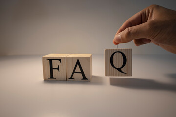 FAQ word from wooden cubes. Spot light and white background. Close up.