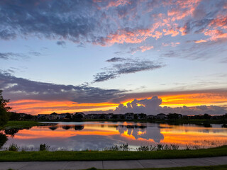Beautiful pink, orange and blue sunset reflecting on a lake in a suburban neighborhood.