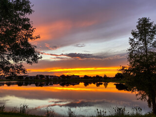 Beautiful pink, orange and blue sunset reflecting on a lake in a suburban neighborhood.