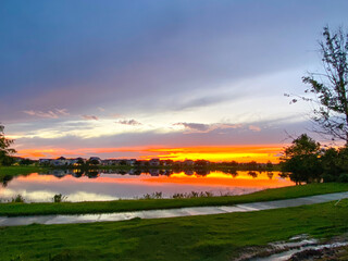 Beautiful pink, orange and blue sunset reflecting on a lake in a suburban neighborhood.