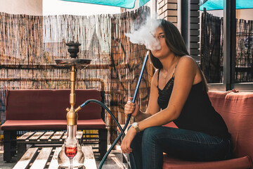 Young beautiful woman smoking hookah and having a great time