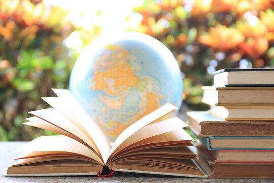 Backlit images of open books on the table Globe as background selective focus and shallow depth of field