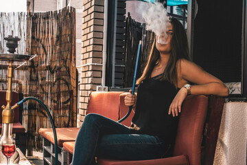 Obraz na płótnie Canvas Young beautiful woman smoking hookah and having a great time
