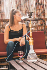 Young beautiful woman smoking hookah and having a great time