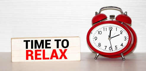 RELAX TIME words on sticker, next to an alarm clock on a wooden table
