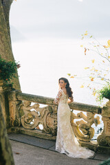 Bride in a wedding dress stands on a beautiful balcony overlooking mountains and lake
