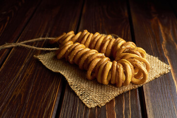 Wheat bagels on a rope on burlap cloth on dark wooden table. Traditional russian food.