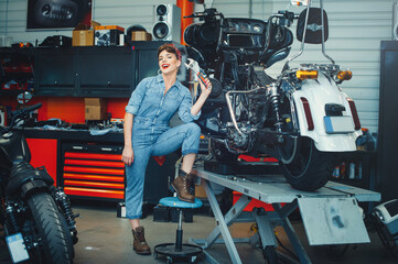Fototapeta premium beautiful girl repairs a motorcycle in a workshop, pin-up style, service and sale