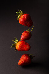 Red strawberries isolated on a black background. Strawberries in flight
