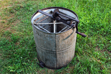 Obraz premium Old empty honey extractor centrifuge on green grass