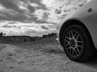 Fototapeta na wymiar car on a dirt road on a background of blue sky and forest