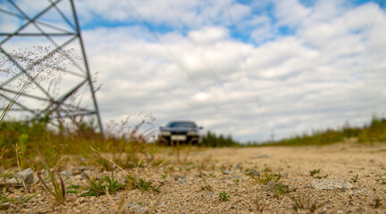 Power line pylon with wires on the background of a blurred car in the distance