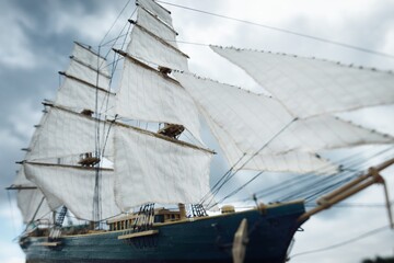 Antiquarian wooden scale model of the clipper tall ship, close-up. Dramatic sky in the background. Traditional craft, souvenirs, hobby, collecting, vintage, modeling. Zero waste concept © Alex Stemmer