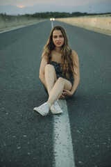 Fototapeta premium Young beautiful rebel woman on empty road at sunset