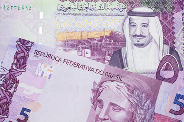 A five Saudi riyal bank note with a pink and purple five Brazilian reais bill.  Shot in macro.