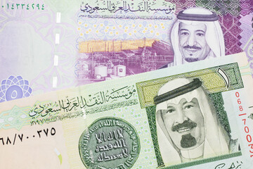 A green one riyal bank note from Saudi Arabia with a colorful five Saudi riyal bank note close up in macro