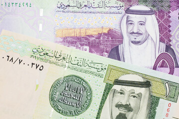 A green one riyal bank note from Saudi Arabia with a colorful five Saudi riyal bank note close up in macro