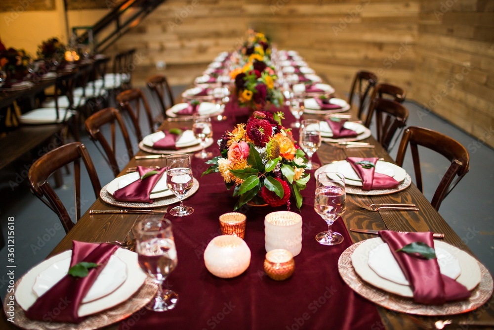 Poster long table covered with dark red texture and plates with splayds