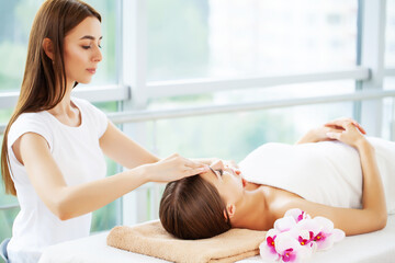 Young woman on rejuvenating facial massage in beauty studio
