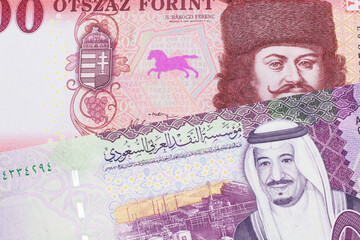 A close up image of a red, one hundred Hungarian forint bill close up with a colorful five riyal...
