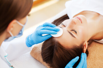 Young woman with beautiful face on facial massage in beauty studio