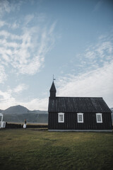 Northen landscapes: Woman contemplating the loneliness of the Budir Church in the Icelandic landscape. Snaefellnes peninsula, region of Vesturland, Iceland.