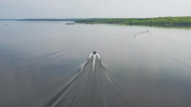 Aerial shot following a fast-moving boat on a calm lake in the late afternoon