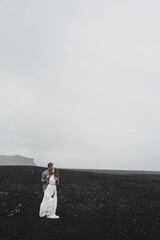 young couple holding hands together and coming to the old plane on the ground black beach in Iceland