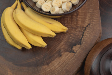 top view of bunch of bananas with stem background, bowl with banana slices