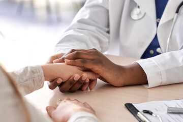 African female doctor hold hand of caucasian woman patient give comfort, express health care sympathy, medical help trust support encourage reassure infertile patient at medical visit, closeup view. - Powered by Adobe