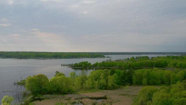 Aerial shot of serene forested island homes on the shores of a great lake