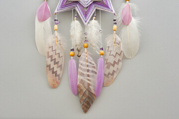Yarn mandala with feathers and amethyst beads on grey background