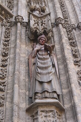 ancient statue of a priest or a pope in stone in the medieval cathedral of Seville in Spain, with a gothic style in perspective