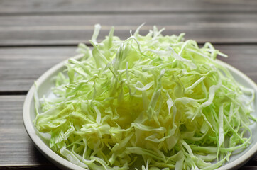 Shredded cabbage salad on wooden ceramic plate over wooden background.