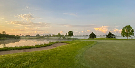 sunrise on golf course hazy sun fog on pond