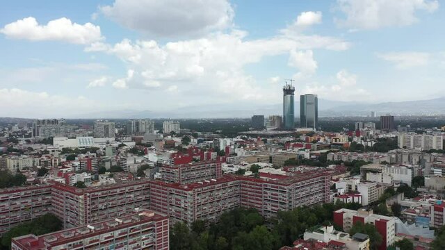 Aerial panoramic view of the tallest building under construction in Mexico City and the city skyline with a blue sky as background.