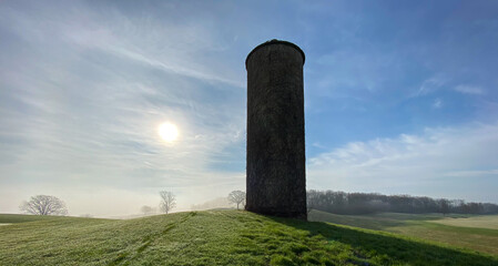 Fototapeta na wymiar old stone silo on golf course early morning fog hazy sun