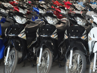 Parking mopeds of different colors. The spotlight of the moped close up