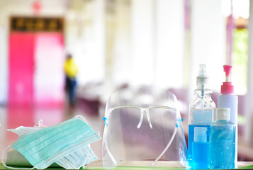 Medical masks, face shield, sanitizer, alcohol gel and hand soap on table in front of balcony to wear and to clean hands to prevent germs and protect coronavirus or covid-19 which is spreading now.