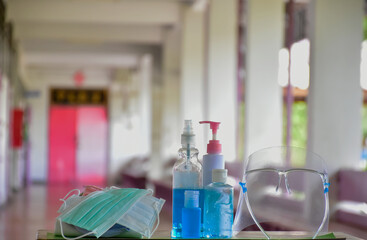 Medical masks, face shield, sanitizer, alcohol gel and hand soap on table in front of balcony to wear and to clean hands to prevent germs and protect coronavirus or covid-19 which is spreading now.