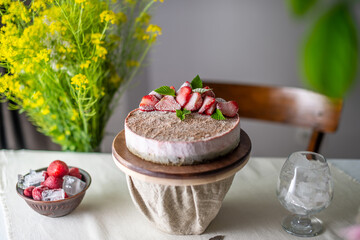 Beautiful frozen mousse cake with ice, flowers and berries on the table. Trendy healthy dessert