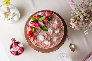 Beautiful frozen mousse cake with ice, flowers and berries on the table. Trendy healthy dessert....