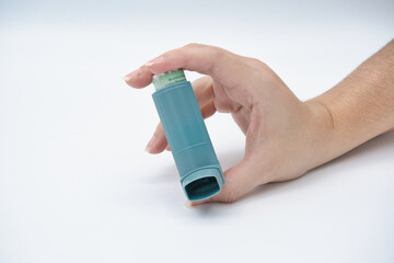 Woman`s hand holding a medical asthma inhaler.