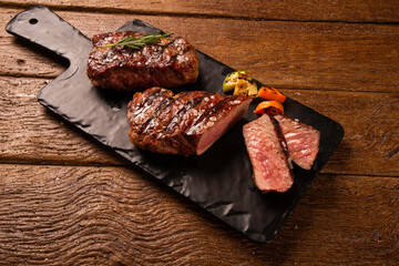 Grilled sliced beef steak on a black cutting board on the wooden table