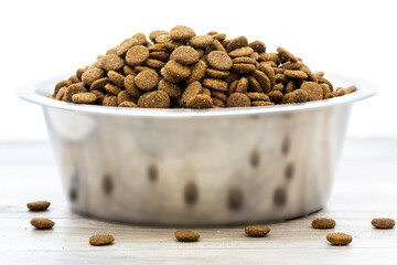 Dry dog and cat food in stainless steel bowl.  Pile of kibbles.