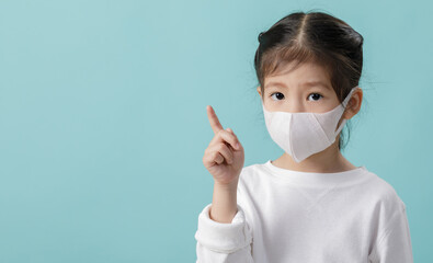 Asian little child girl wearing respirator mask to protect coronavirus outbreak and pointing hand...