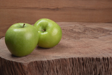 two green apples on wooden trunk table, in closeup