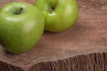 two green apples on wooden trunk table, in closeup