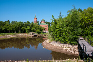 Fototapeta na wymiar Russian village, summer landscape bridge over the lake and the old Orthodox Church