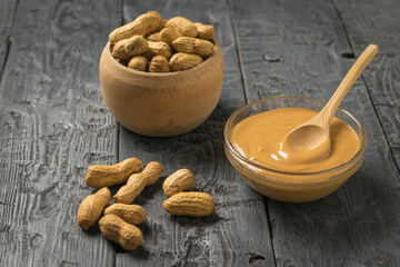 Glass bowl with peanut paste and wooden bowl with peanut fruit.